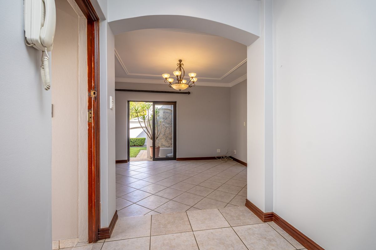An empty living area featuring tiled floors, an arched entryway, and a sliding glass door leading to the exterior.