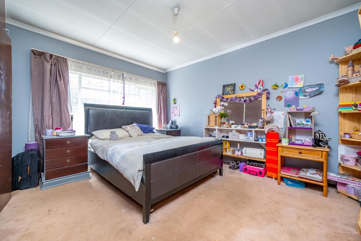 A spacious bedroom featuring carpet flooring and a large window, offering a blank canvas for potential updates and interior design improvements.