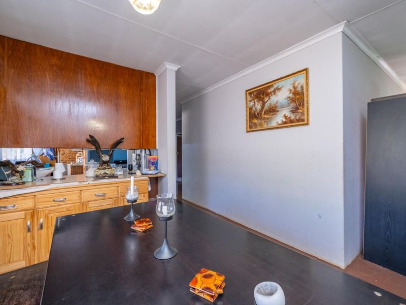 A dated kitchen area featuring wooden cabinetry, a mirror splashback, and laminate countertops, offering potential for a modern renovation.