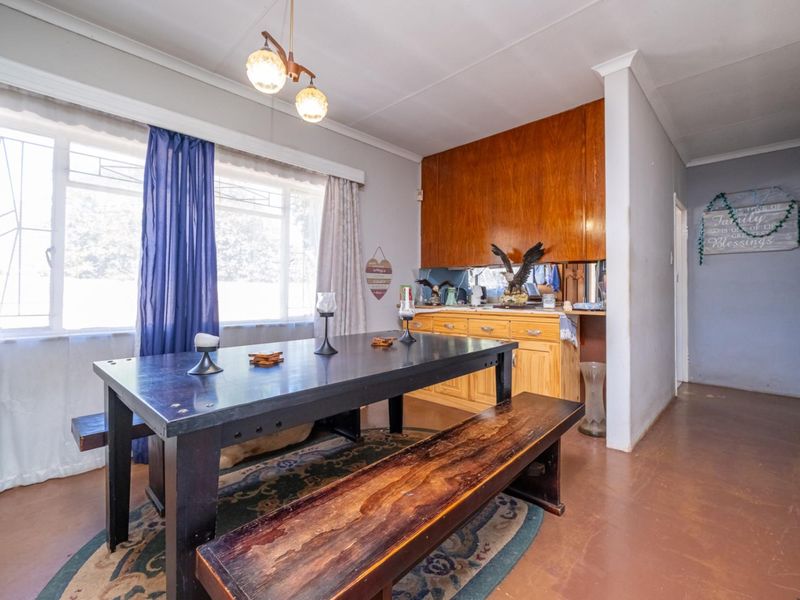 Dining area featuring built-in wooden cabinetry, large windows with security bars, and neutral wall finishes.