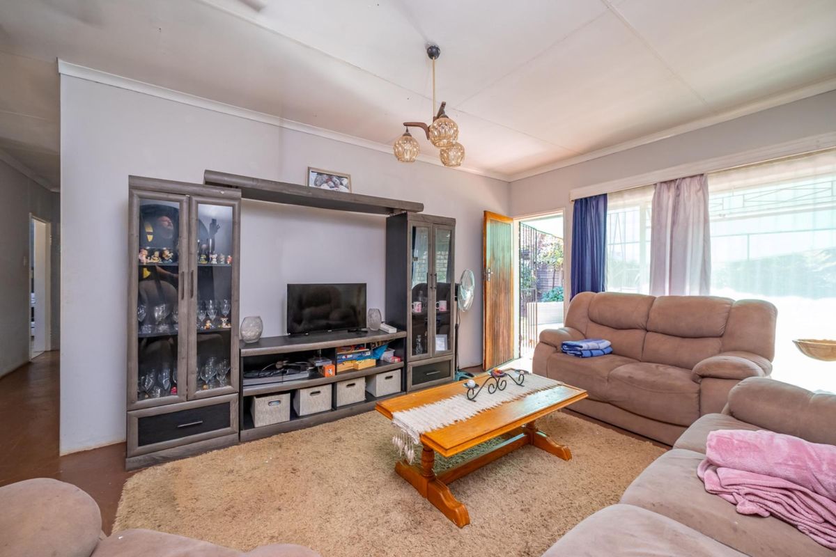 A living room featuring carpeted flooring, a central light fixture, and access to an exterior security gate.