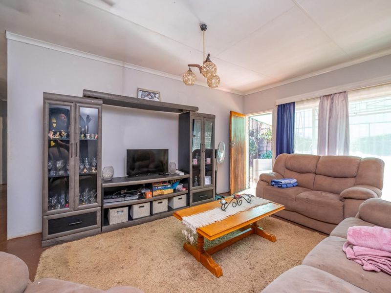 A living room featuring carpeted flooring, a central light fixture, and access to an exterior security gate.