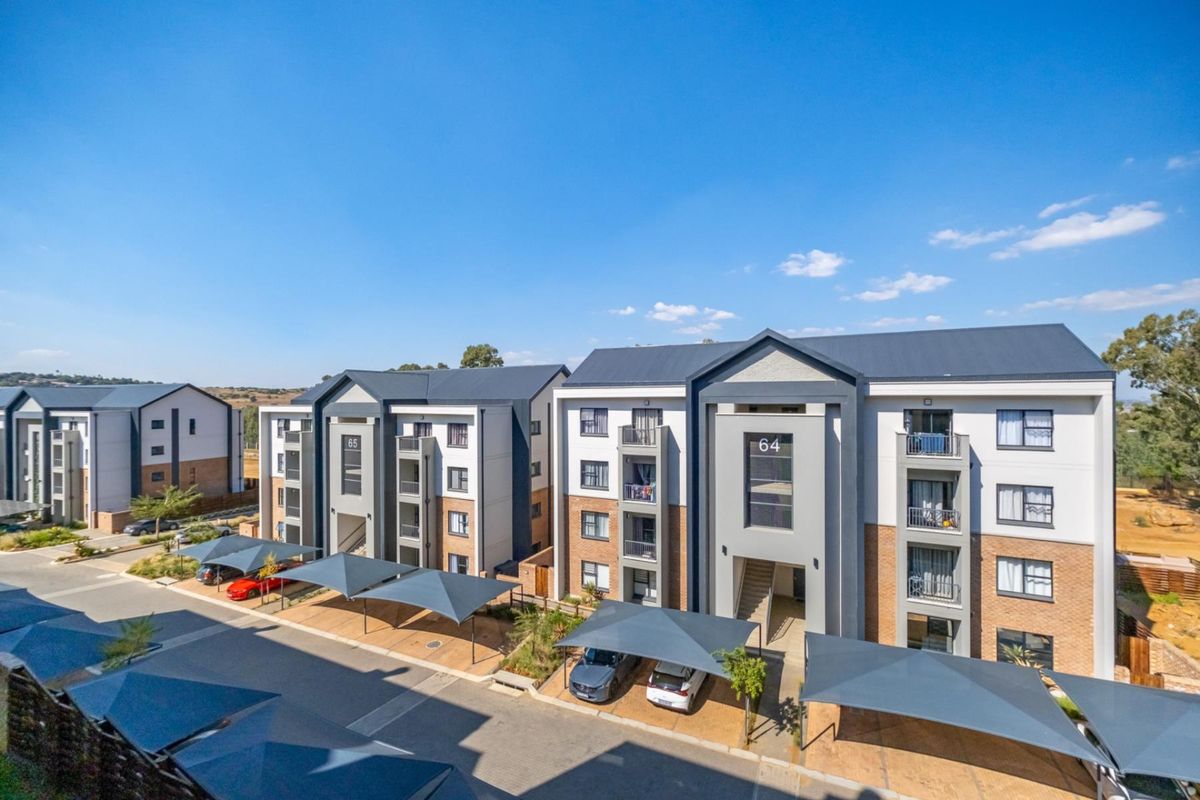 An elevated view of a modern apartment complex featuring multi-story buildings with covered parking bays and paved access roads.