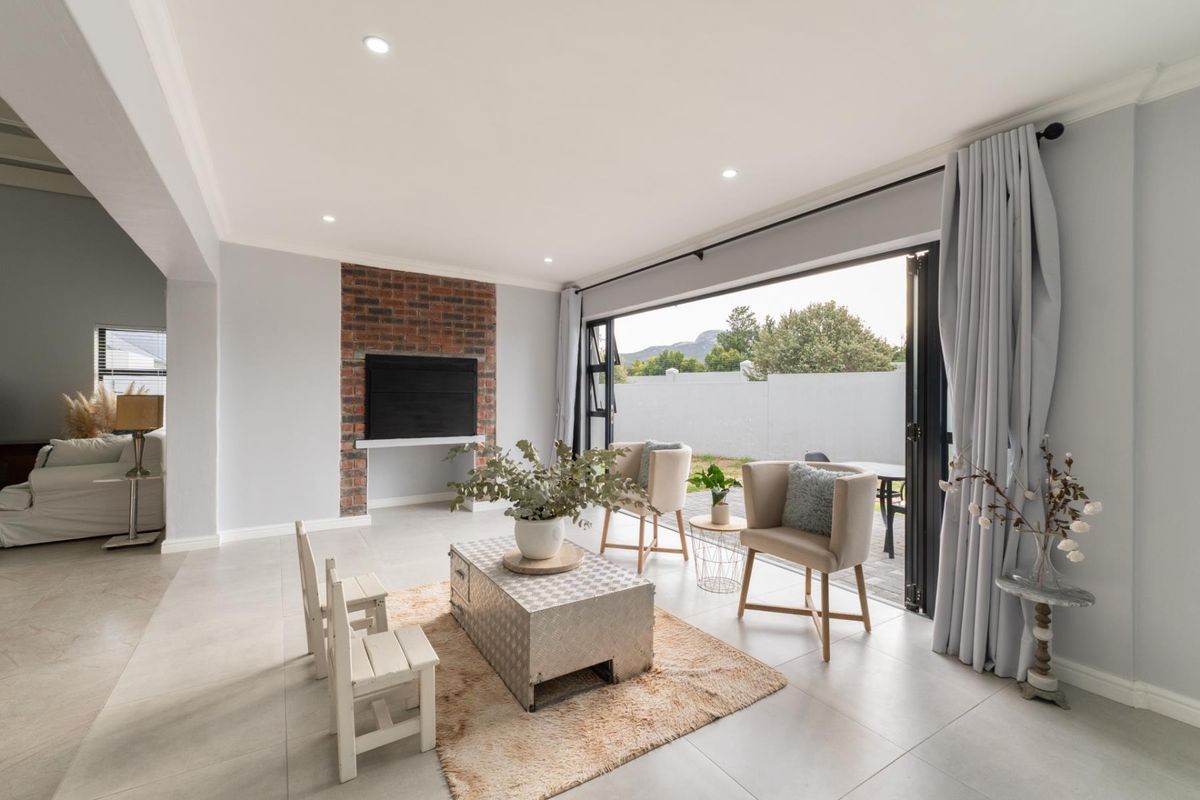Spacious living area featuring a brick fireplace surround and large folding doors that open onto an outdoor patio area.
