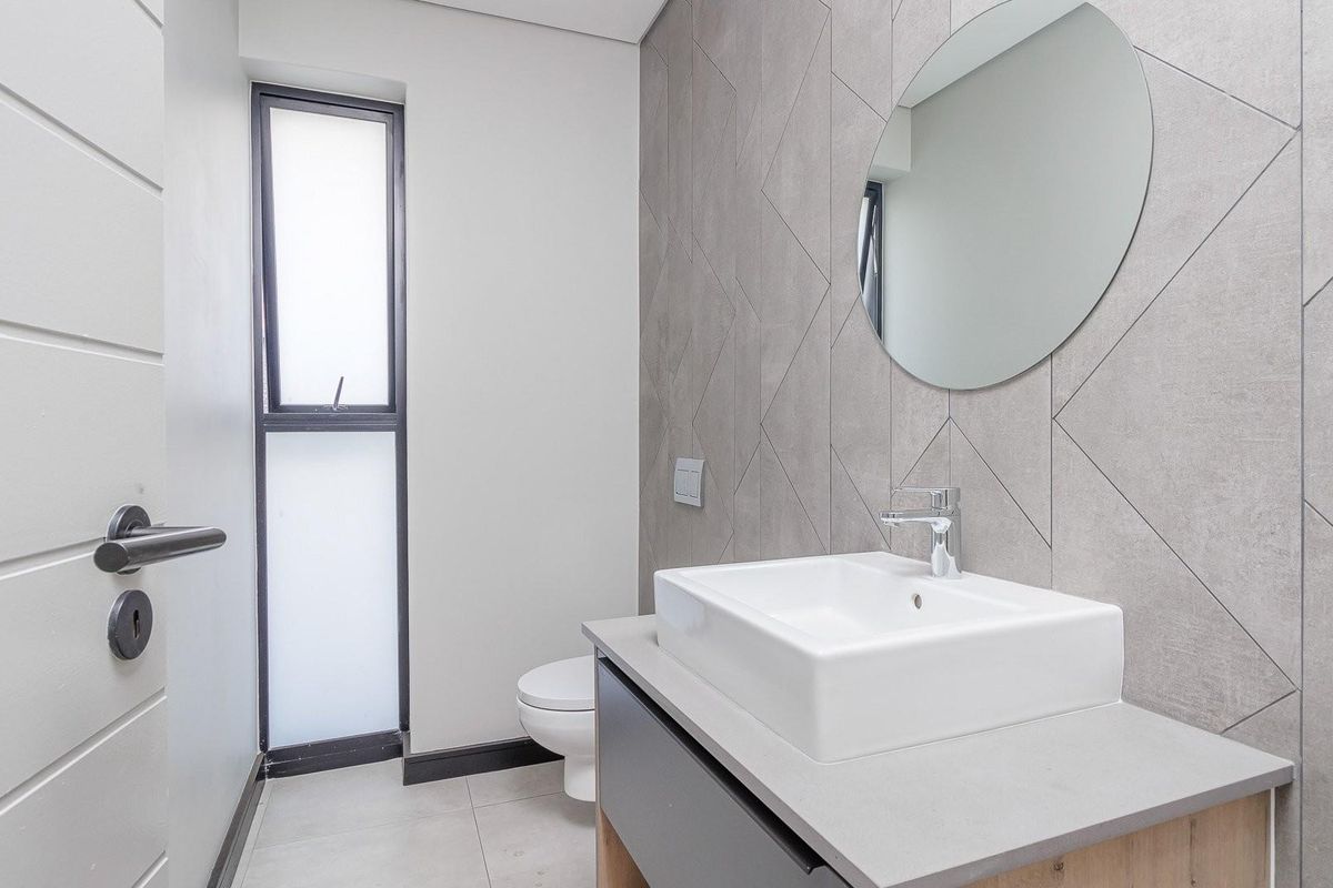 Modern bathroom featuring a contemporary vanity with a vessel sink, geometric wall tiling, and a sleek toilet.