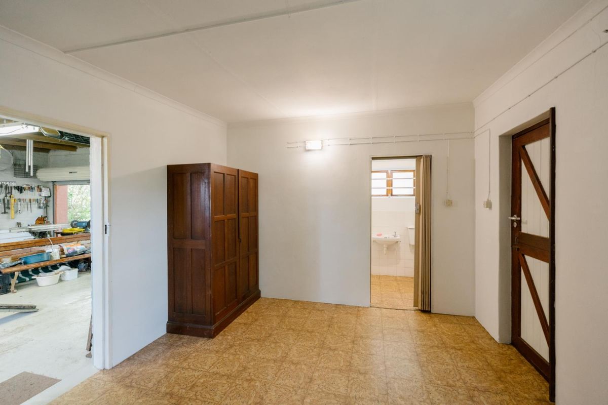 A functional utility space or bedroom featuring vinyl flooring, a folding door leading to an en-suite, and direct access to an adjacent workshop area.
