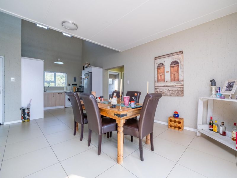 Open-plan living and dining area featuring tiled floors, vaulted ceilings with skylights, and an integrated kitchen space with functional cabinetry.