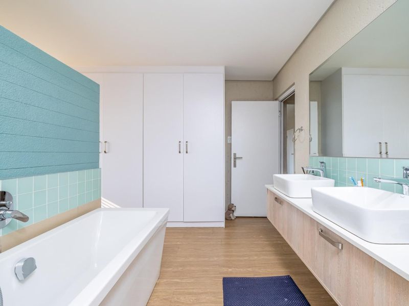 Modern bathroom featuring a double vanity with vessel sinks, built-in storage cupboards, and a sleek freestanding bathtub with contemporary fixtures.
