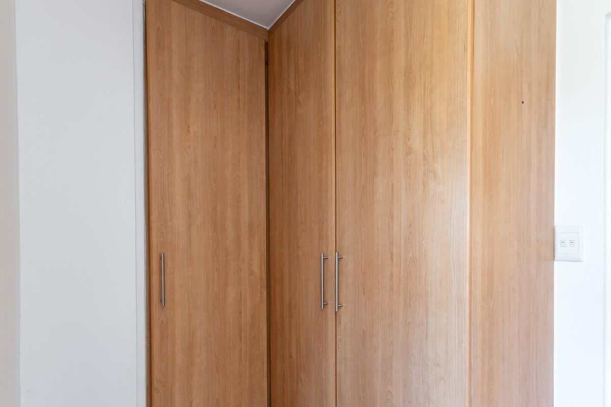 A bedroom featuring built-in wooden cabinetry with modern metal handles, providing ample storage space.