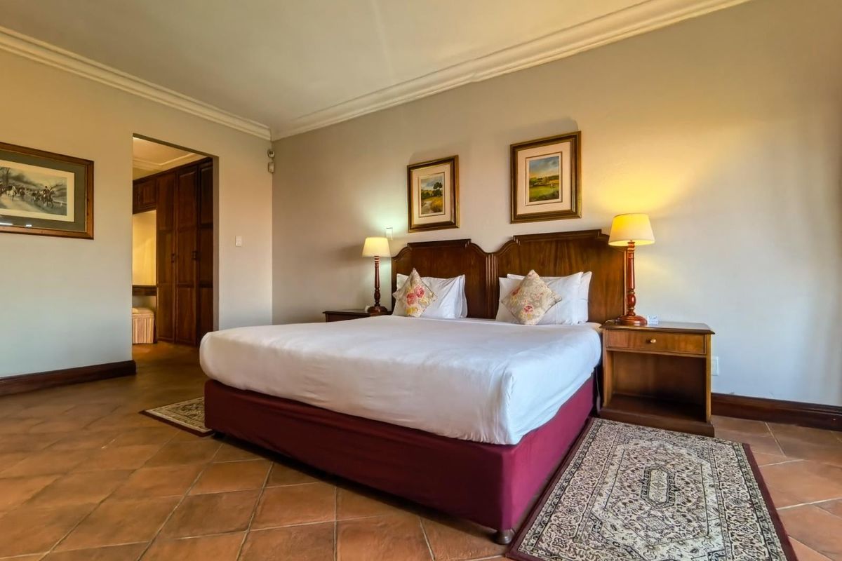 Spacious bedroom featuring traditional terracotta floor tiles, decorative cove cornicing, and access to a walk-in closet area with built-in cabinetry.