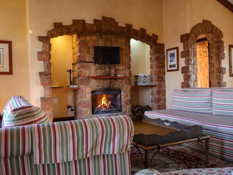 A cozy living room featuring a prominent stone fireplace with integrated archways and built-in shelving, creating a rustic and warm atmosphere.