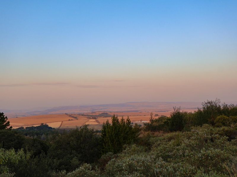 A scenic, elevated landscape view overlooking rolling hills and rural terrain at sunset.
