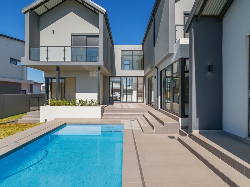 Modern rear exterior featuring a swimming pool, tiled patio area, and contemporary multi-level architecture with large glass sliding doors.