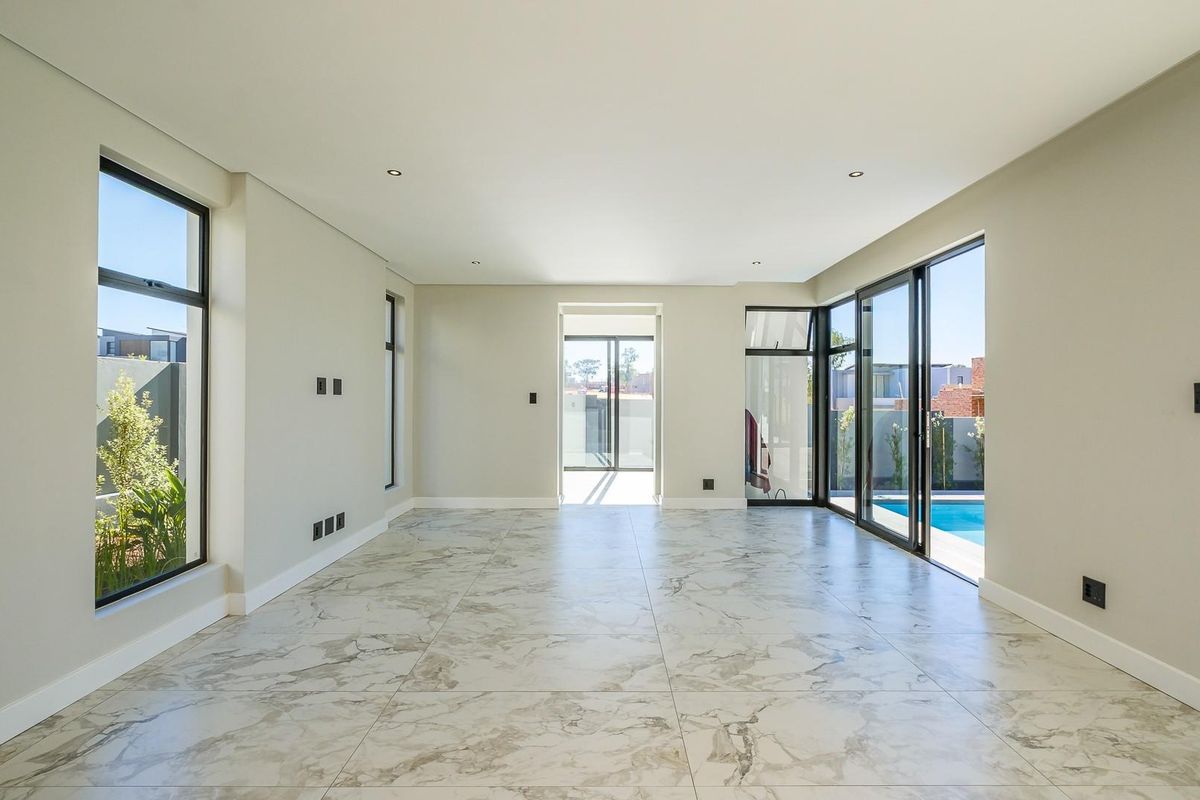 Spacious, light-filled living area featuring modern marble-look floor tiles, recessed lighting, and large sliding doors providing seamless access to the pool area.