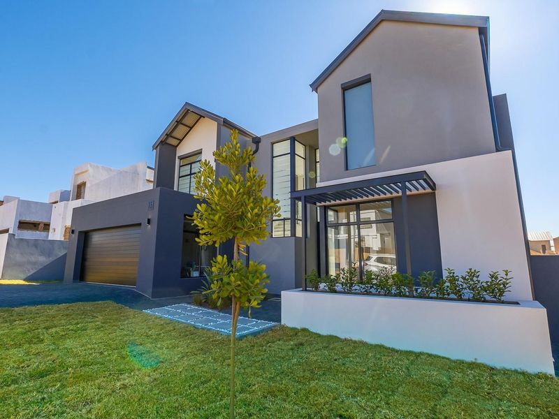 Modern double-story residential home featuring a contemporary facade, integrated double garage, paved driveway, and manicured front lawn.