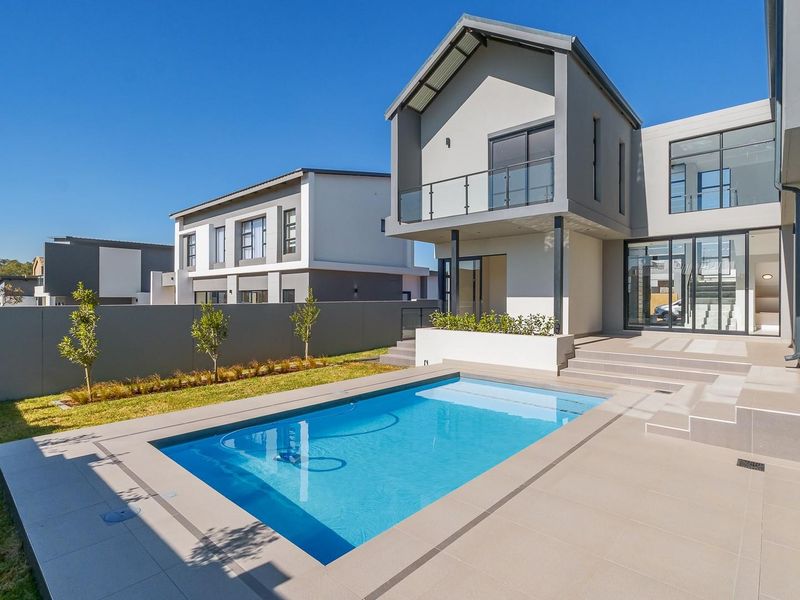 Modern rear exterior featuring a swimming pool, tiled patio area, and a contemporary two-story house facade with large glass sliding doors.