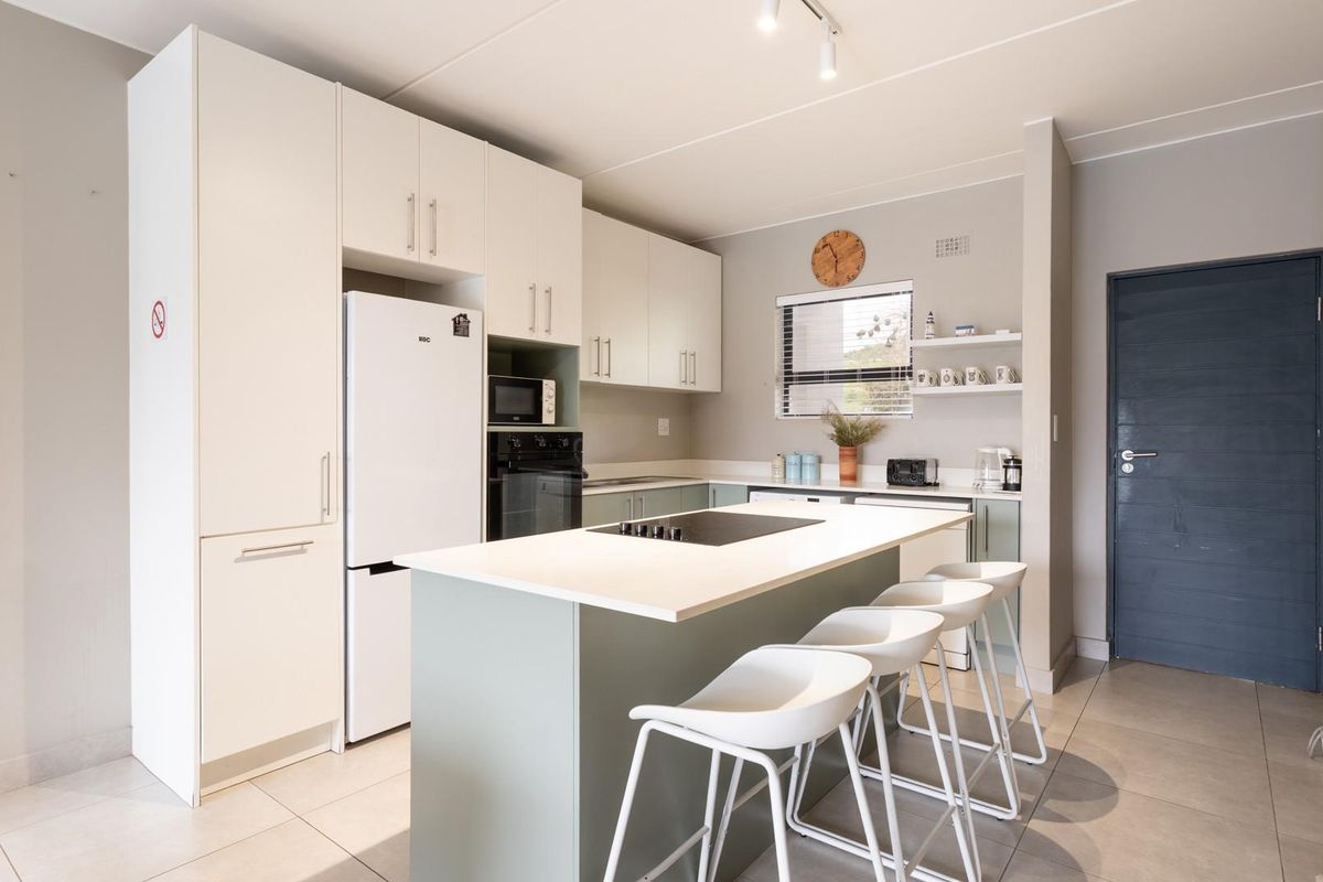 Modern kitchen featuring a central island with a built-in hob, sleek cabinetry, and tiled flooring, offering a functional and contemporary cooking space.