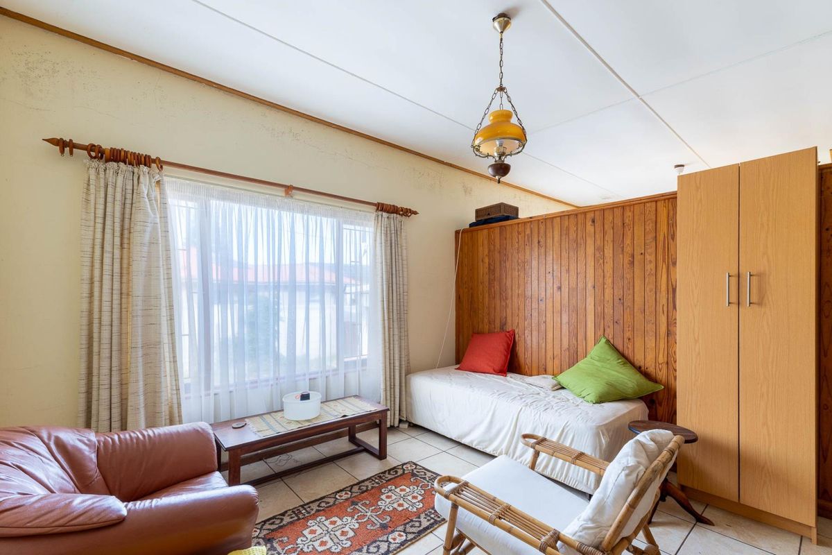 A bedroom featuring wood paneling, tiled flooring, and a built-in wardrobe, requiring cosmetic updates to the walls and ceiling.