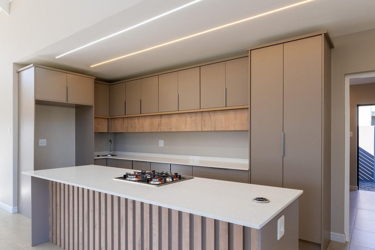 Modern kitchen featuring a central island with a built-in gas hob, sleek cabinetry, stone countertops, and integrated lighting.