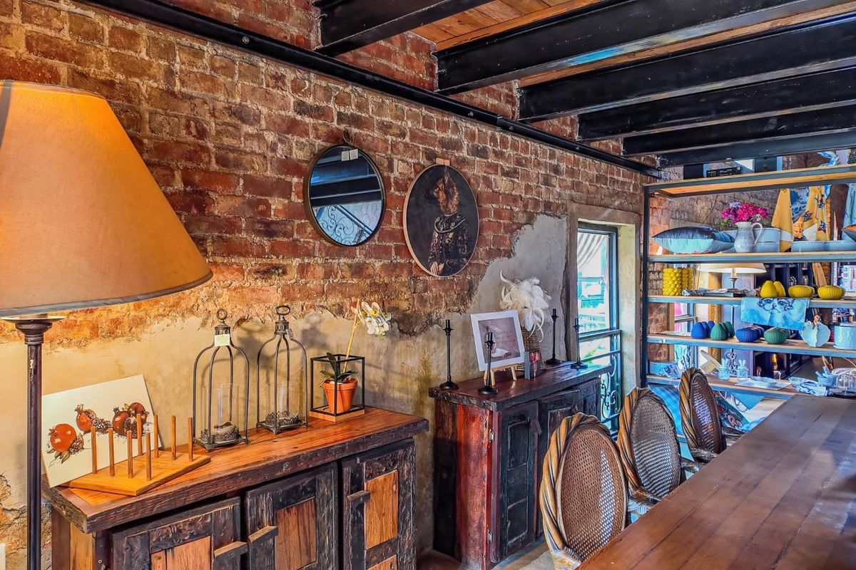 A rustic interior space featuring exposed brick walls, industrial-style black steel ceiling beams, and wooden cabinetry, creating a warm, character-filled commercial atmosphere.