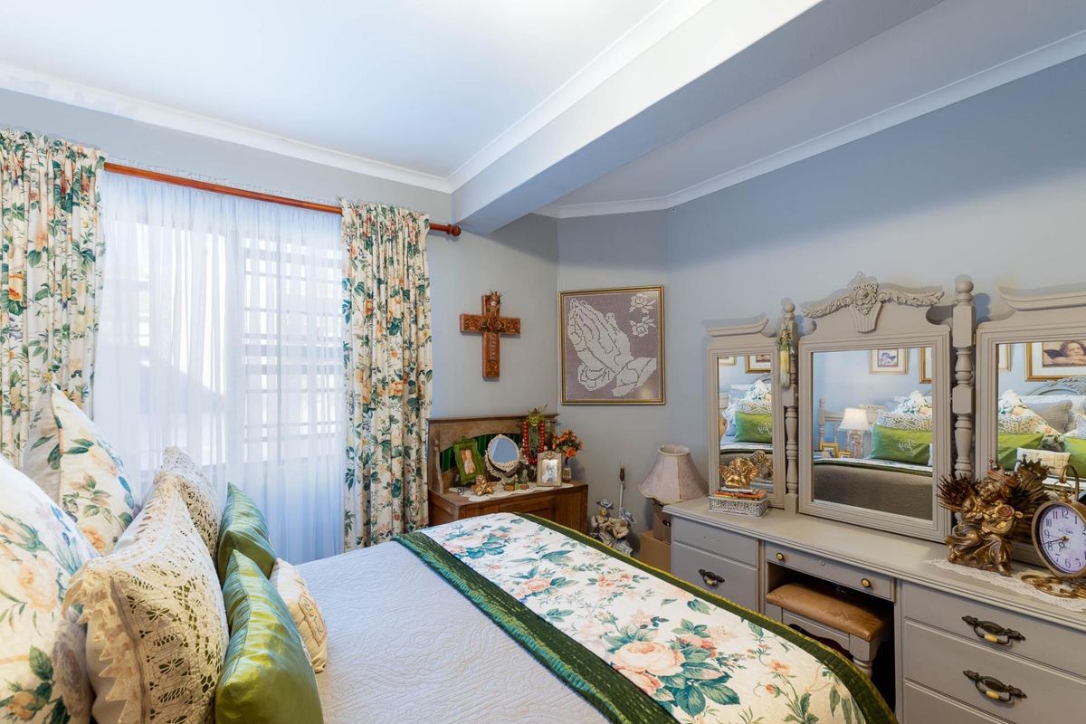 A well-maintained bedroom featuring neutral wall tones, crown molding, and a large window with natural light.