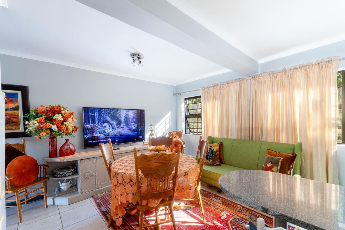 A bright living and dining area featuring tiled flooring, neutral wall tones, and large windows with curtain treatments.