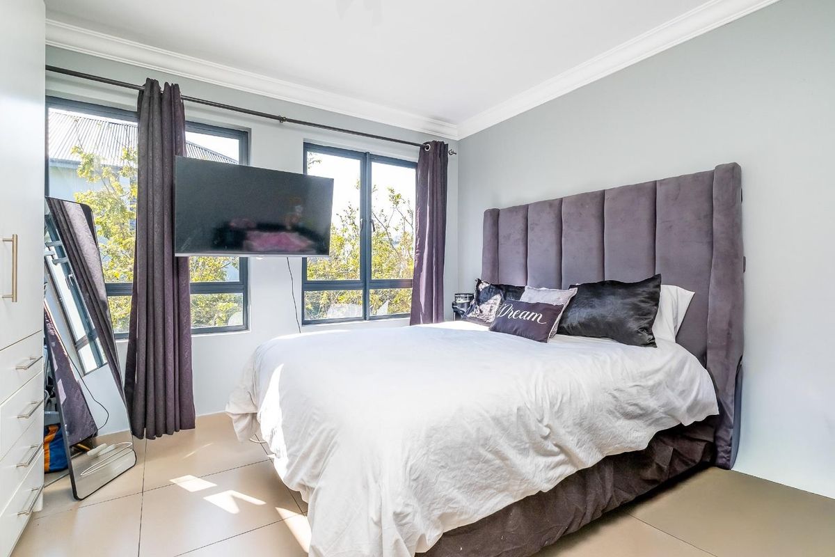 A well-lit bedroom featuring large windows, built-in cabinetry, and crown molding, providing a comfortable and functional living space.