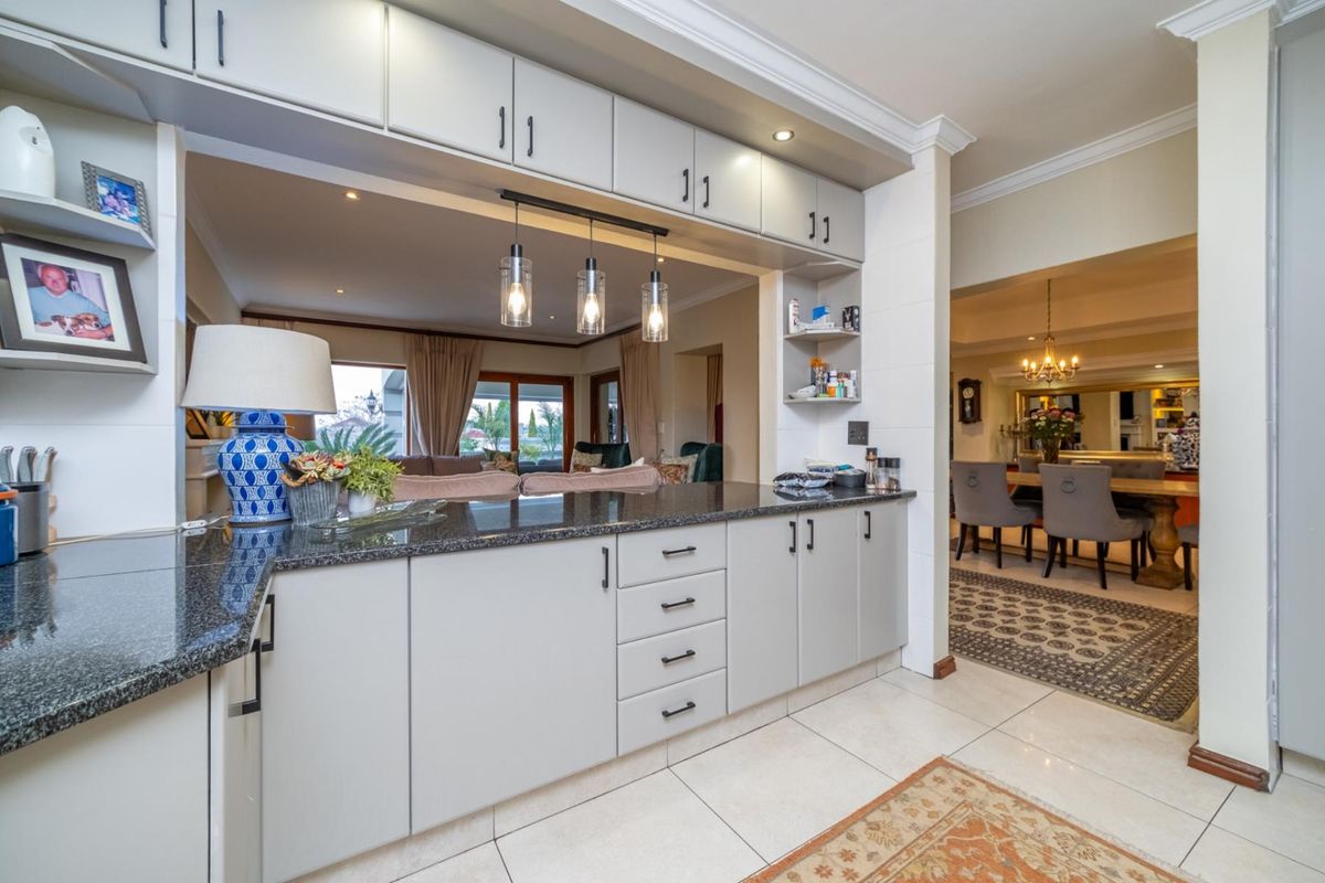 A well-appointed kitchen featuring granite countertops, modern cabinetry, and integrated lighting, seamlessly flowing into the adjacent dining and living areas.