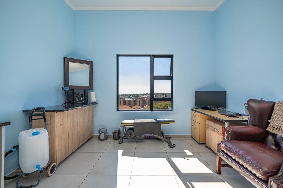 A versatile room featuring tiled flooring, a built-in granite-topped cabinet, and a window offering an elevated urban view.