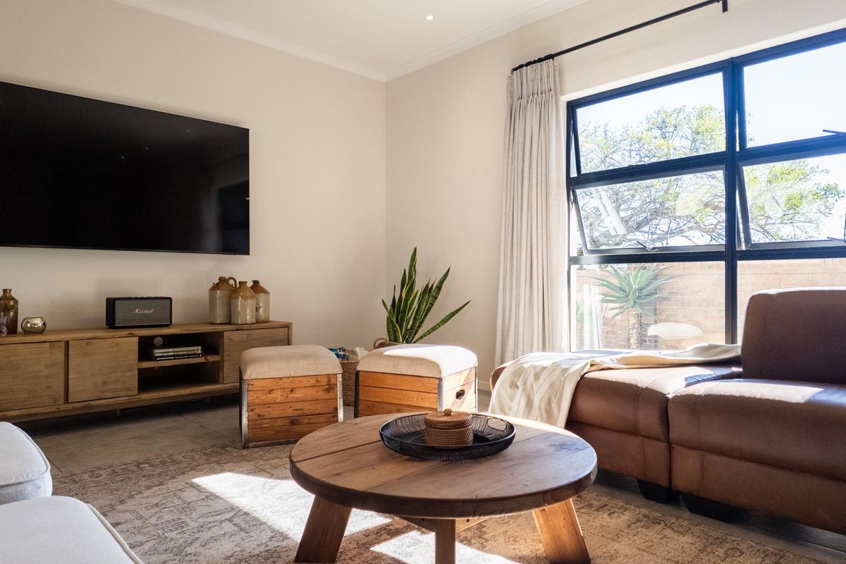 A bright and modern living room featuring large black-framed windows, neutral walls, and recessed ceiling lighting, creating a comfortable and inviting atmosphere.