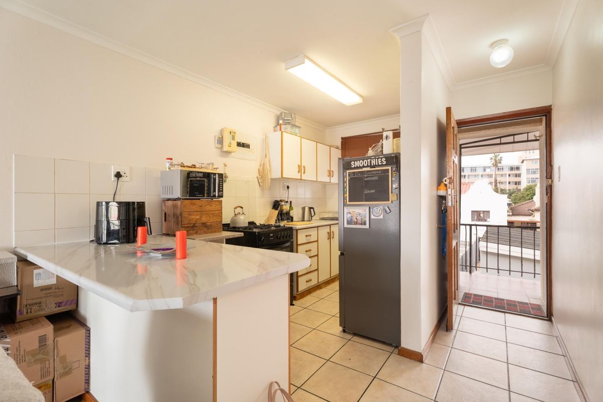 Functional kitchen featuring tiled flooring, ample cabinetry, and a gas stove, with direct access to an outdoor balcony area.