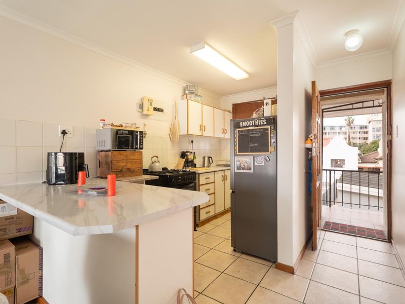 Functional kitchen featuring tiled flooring, ample cabinetry, and a gas stove, with direct access to an outdoor balcony area.