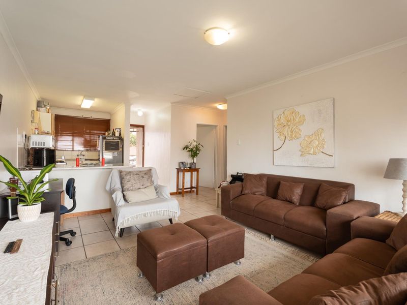 An open-plan living area featuring tiled flooring, a functional kitchen with cabinetry, and a breakfast counter, creating a cohesive and versatile living space.