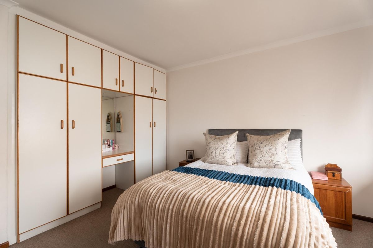 A bedroom featuring built-in cupboards with an integrated vanity area and carpeted flooring.