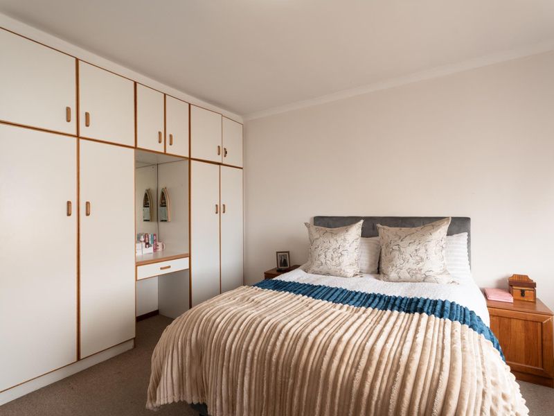 A bedroom featuring built-in cupboards with an integrated vanity area and carpeted flooring.