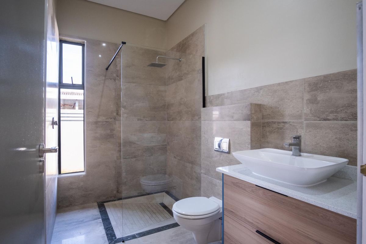 Modern bathroom featuring a walk-in glass shower, wall-mounted toilet, and a contemporary vanity with a vessel sink.