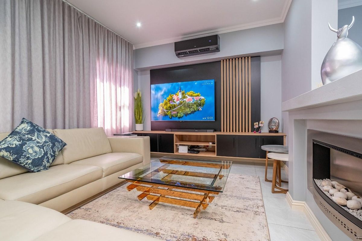 Modern living room featuring a built-in media console, decorative timber slat wall paneling, a sleek fireplace, and a wall-mounted air conditioning unit.