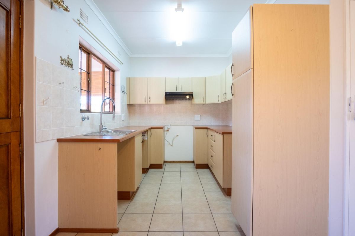 Functional kitchen featuring light wood cabinetry, tiled splashbacks, tiled flooring, and a stainless steel sink with a gooseneck faucet.
