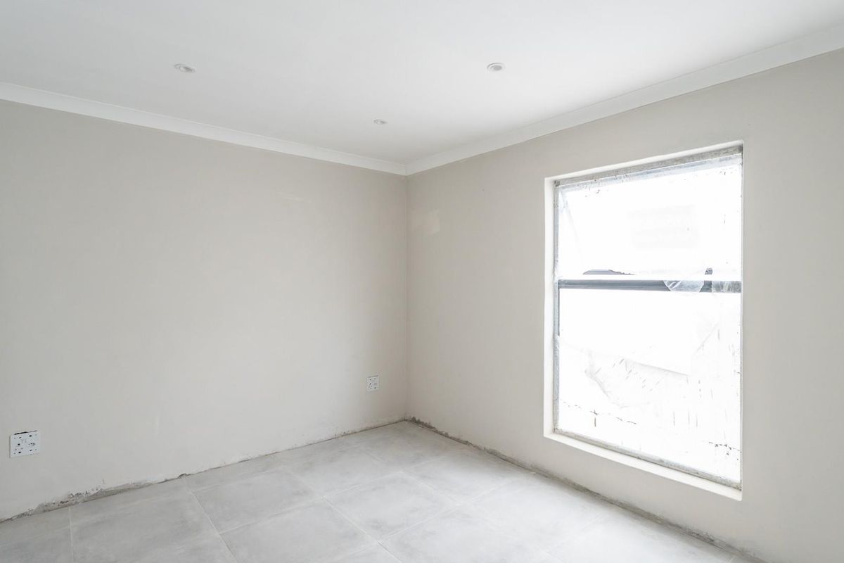 A bright, empty bedroom featuring neutral walls, tiled flooring, and recessed ceiling lighting, ready for personalization.