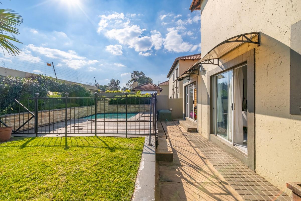 Rear exterior view of the townhouse featuring a paved patio, swimming pool with safety fencing, and direct access via sliding glass doors.