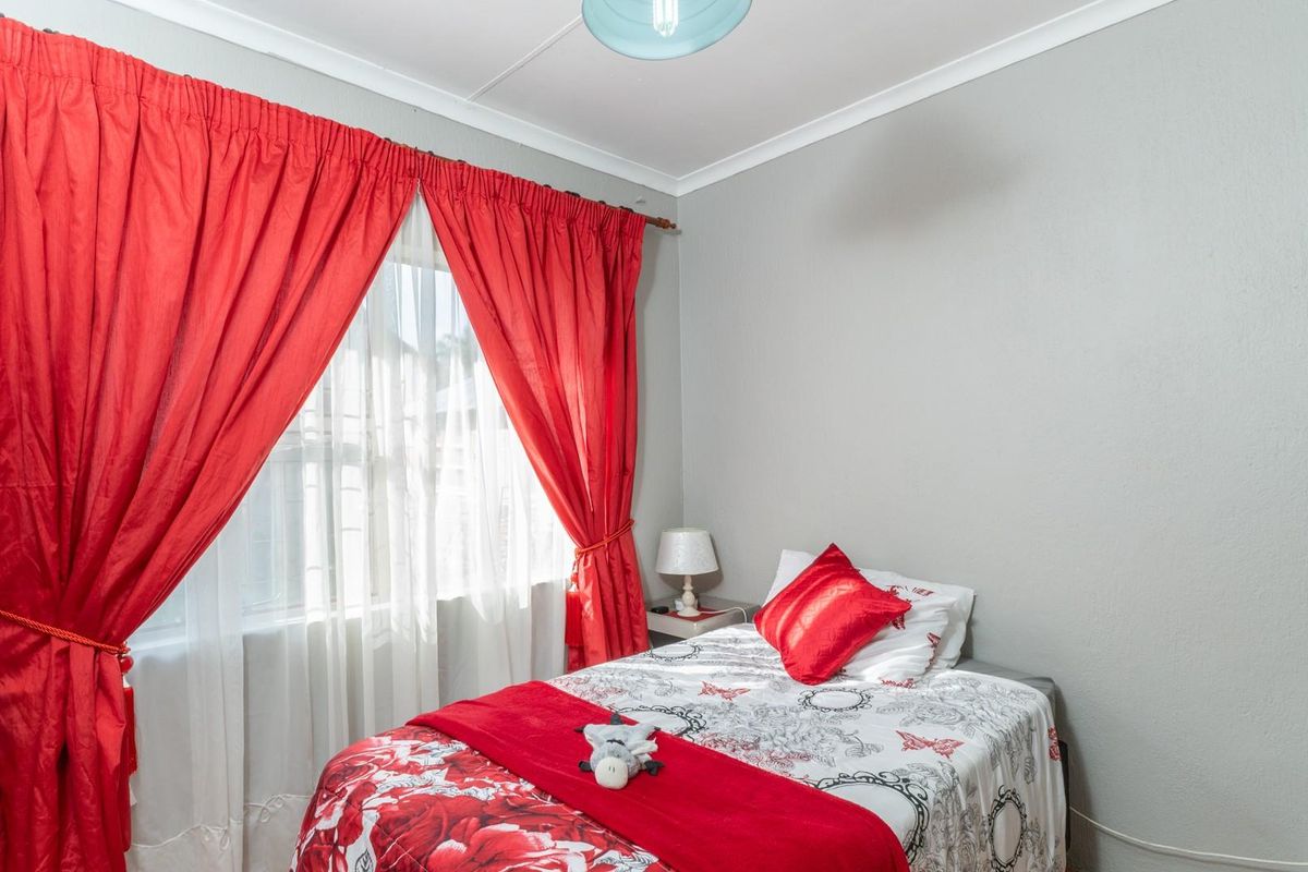 A standard bedroom featuring neutral wall paint, coved ceilings, and a window with curtain rod fixtures.