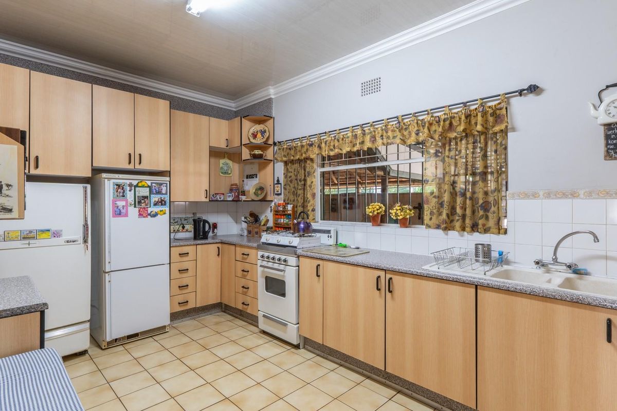 A functional kitchen featuring light wood-finish cabinetry, laminate countertops, a double-basin sink, and a freestanding stove with an integrated oven.