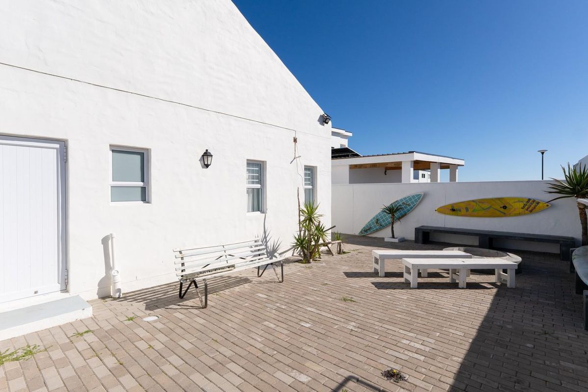 A well-maintained rear paved patio area featuring a white exterior wall, built-in bench seating, and a clean, open outdoor space.
