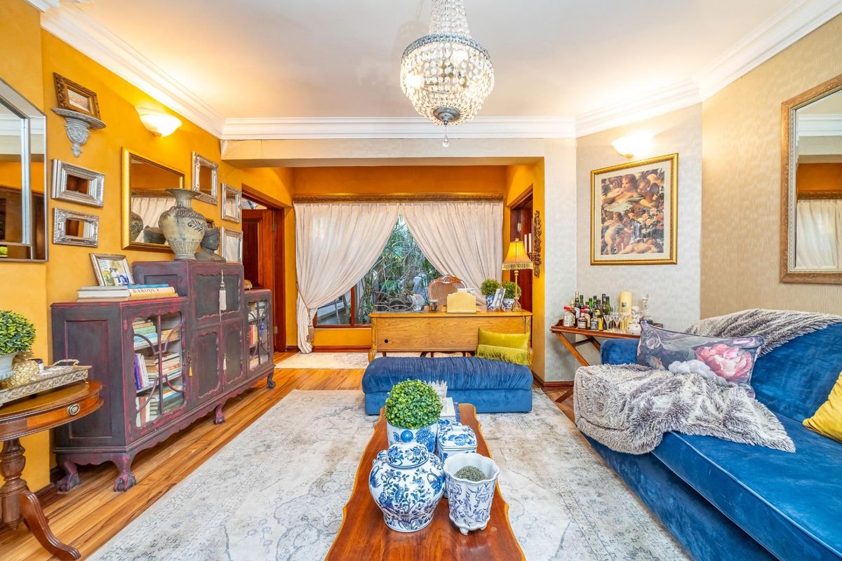A well-maintained living room featuring hardwood flooring, crown molding, and a classic crystal chandelier, offering a warm and inviting atmosphere.