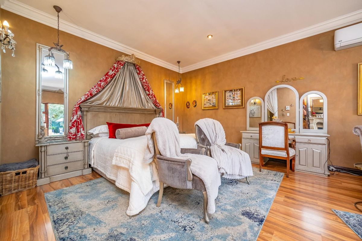 Spacious bedroom featuring warm-toned walls, laminate flooring, crown molding, and a wall-mounted air conditioning unit for climate control.