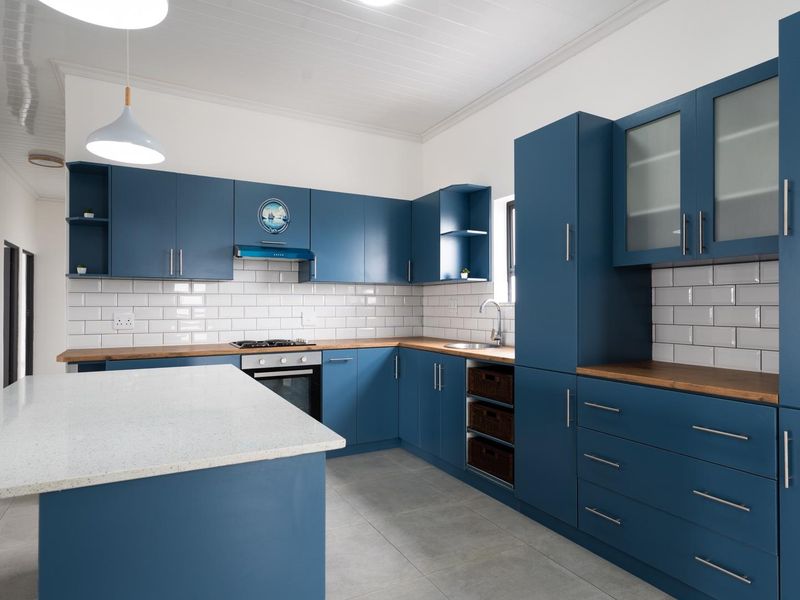 Modern kitchen featuring blue cabinetry, subway tile backsplash, wooden countertops, a central island, and integrated appliances.