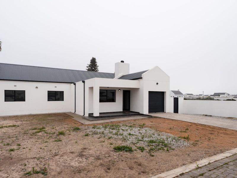 A modern single-story home featuring a white facade, corrugated metal roof, integrated garage, and a paved driveway with an unlandscaped front garden area.