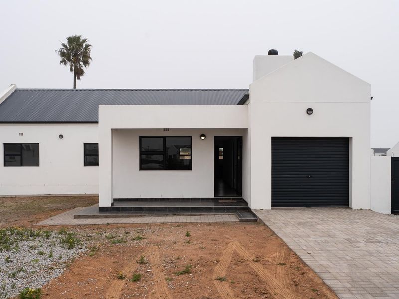 Front elevation of a modern white house featuring a single garage, paved driveway, and a covered entrance porch with dark tiled flooring.