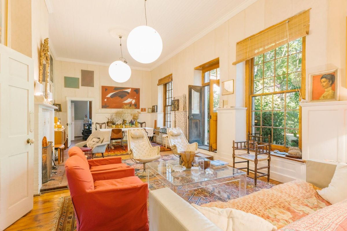 Spacious living area featuring high ceilings, large sash windows, timber flooring, and a classic fireplace, creating a bright and inviting atmosphere.