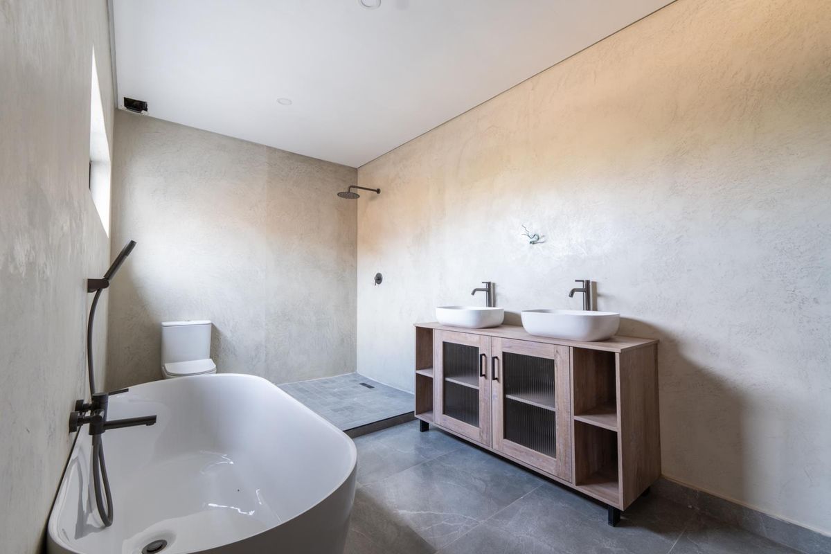Modern bathroom featuring a freestanding bathtub, walk-in shower with rainfall head, and a double vanity with vessel sinks and textured wall finishes.